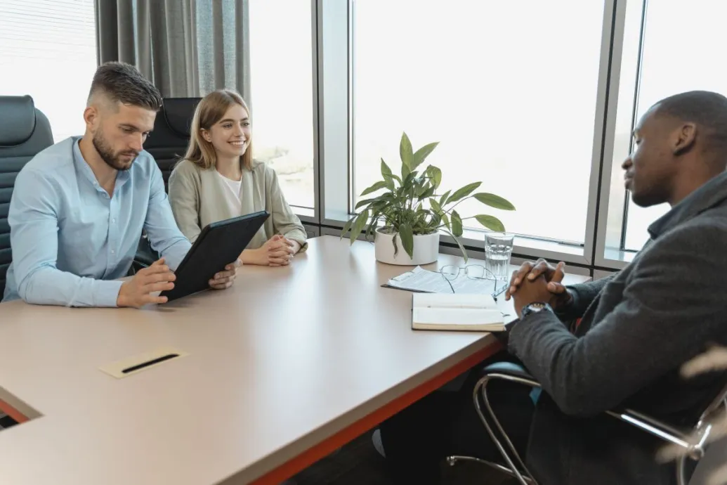 A business interview with three people in a modern office room, highlighting collaboration.