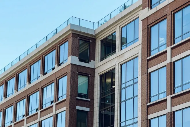 Contemporary office building exterior featuring large glass windows and green surroundings.