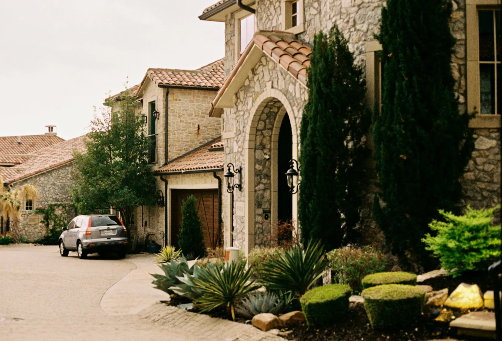 Elegant stone mansion with greenery and gated entry in Dallas, Texas.