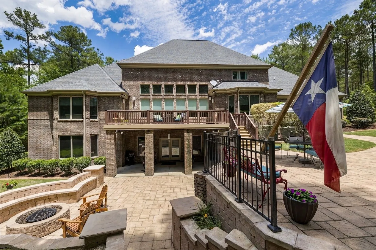 Luxury brick house featuring a large terrace, fire pit, and well-maintained garden.