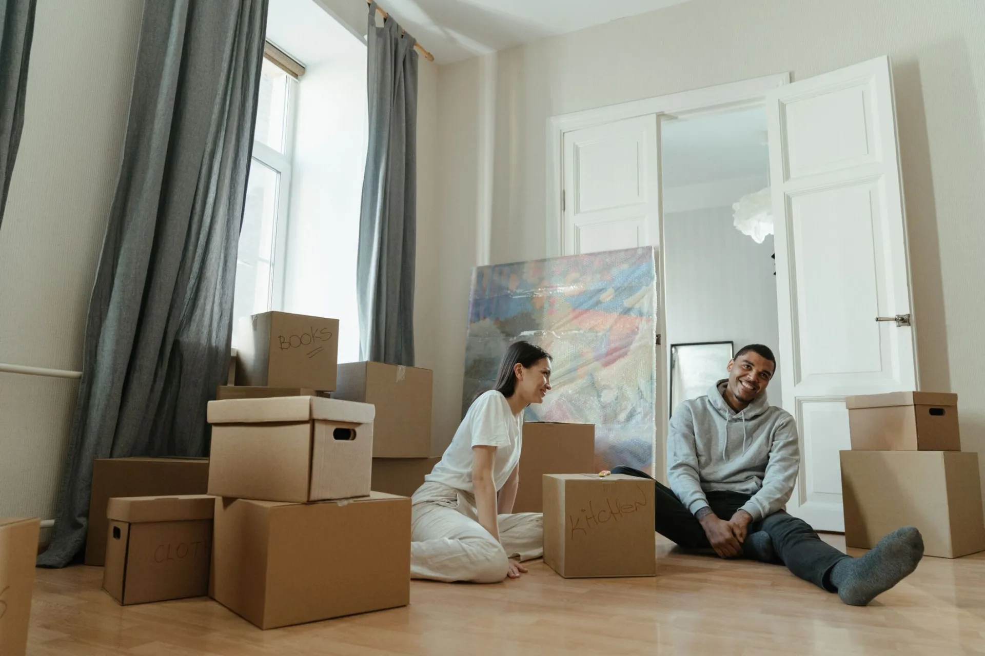 A happy couple surrounded by boxes while moving into a new apartment, symbolizing fresh beginnings.