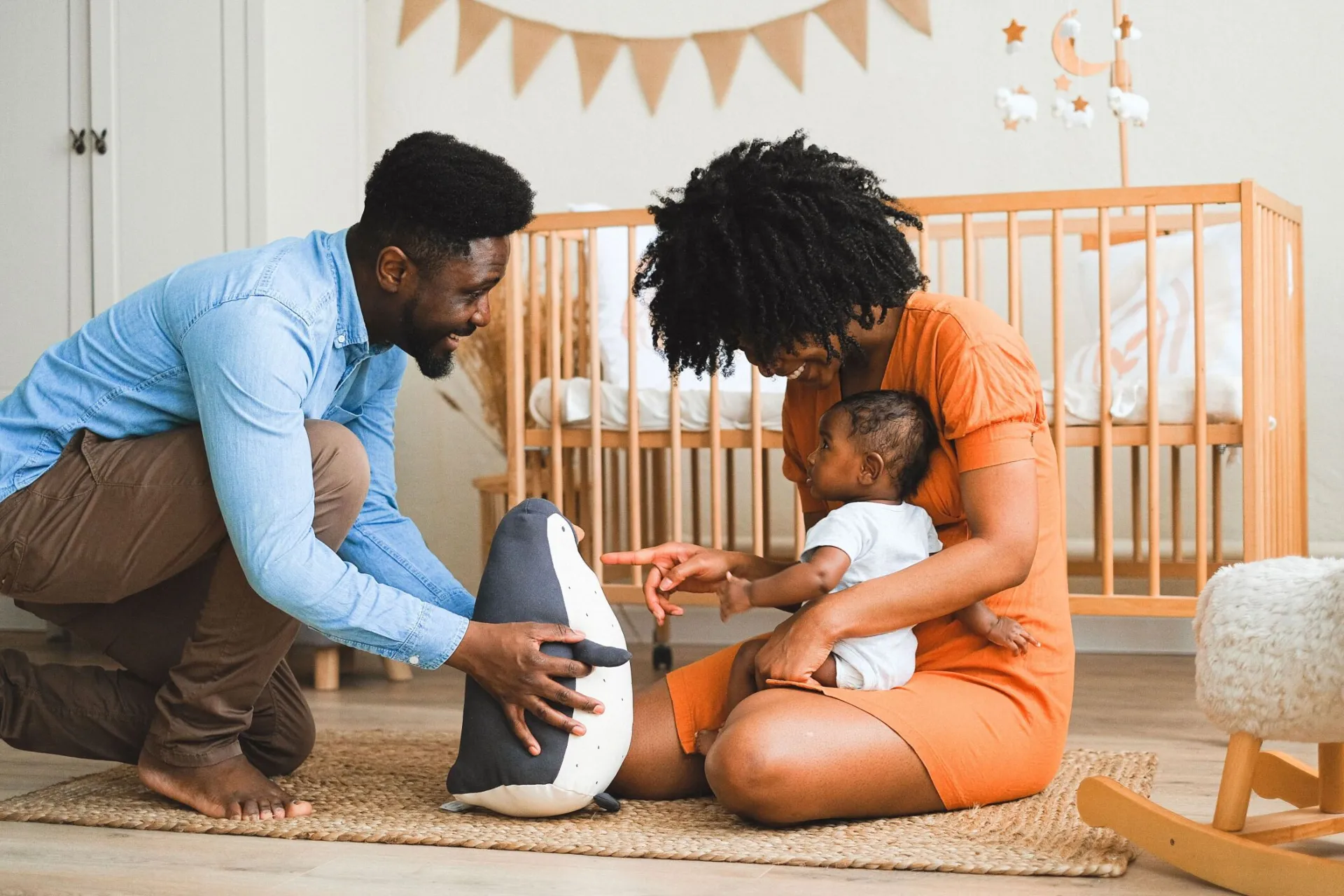 Cheerful parents bonding with baby in modern nursery, experiencing precious moments.