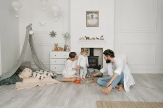 Warm family scene of parents playing with their daughter in a cozy white room.