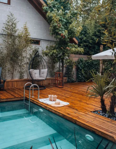 Serene backyard retreat with pool, wooden deck, and lush greenery.