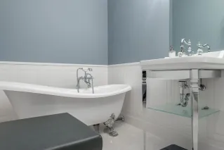 Interior of stylish bathroom with empty white bathtub and sink in luxury modern flat