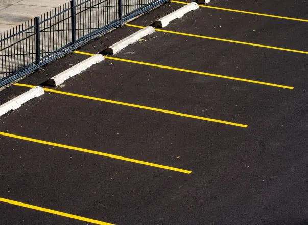 Top view of an empty parking lot with yellow lines and a metal fence, perfect for urban scenes.