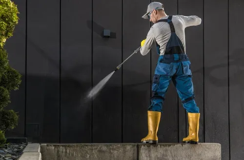 worker-cleaning-modern-building-dark-wall-using-pressure-washer