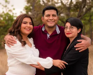 A joyful family trio hugging in a natural outdoor setting, symbolizing love and togetherness.