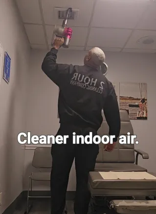Man cleaning an office air vent